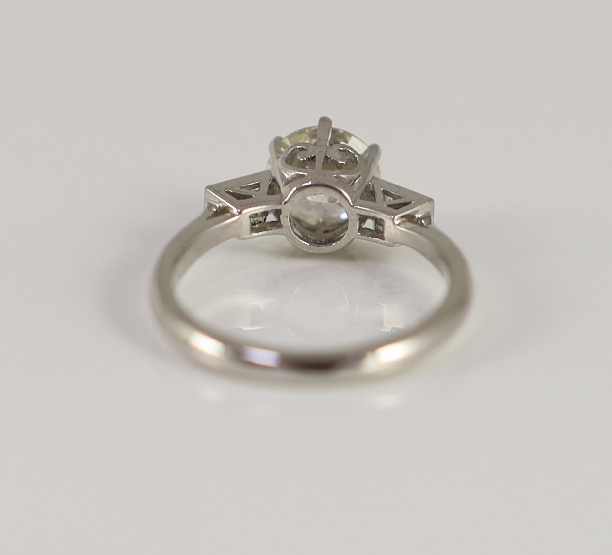 A platinum and single stone diamond ring, with baguette cut diamond set shoulders